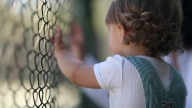Child watching game leaning on fence, video 
