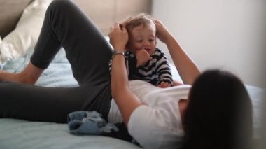 Mother and child in bed in the morning. Happy toddler boy jumping in bed
