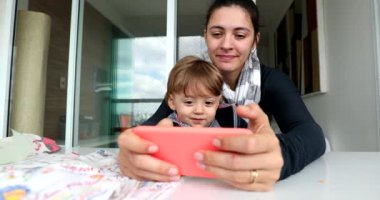 Parent and child using cellphone. Mother and toddler holding smartphone