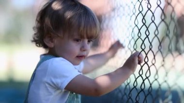 Child watching game leaning on fence, video 
