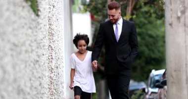 Güzel baba ve melez oğul şehir kaldırımında birlikte yürüyorlar, ebeveyn ve etnik çeşitlilikte genç çocuk kaynaşıyor.