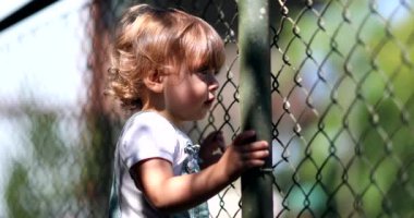 Child watching game leaning on fence, video 