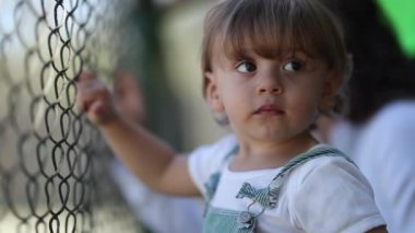 Child watching game leaning on fence, video 
