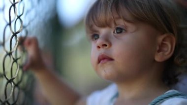 Child watching game leaning on fence, video 