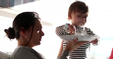 Funny baby toddler feeding mother reversing the roles. Adorable child feeds mom food