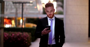 İşadamı geceleri cep telefonunu kontrol ediyor. Şirket merkezinde yürüyor.