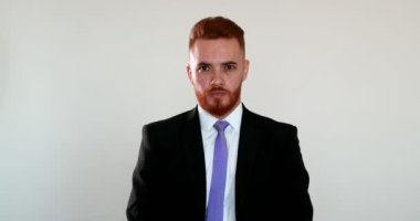 Hüsrana uğramış iş adamı kameraya bakıyor, başını sallıyor, utançla yüzünü kapatıyor.