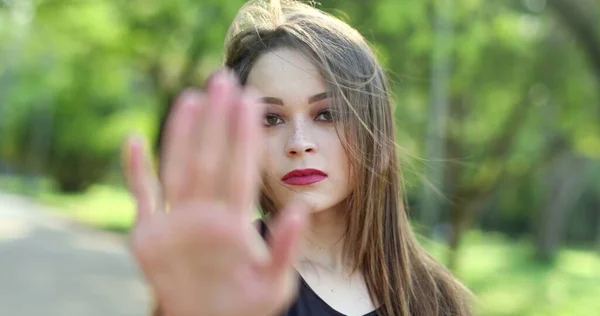 Millennial girl signalling to STOP with hand, woman waving finger gesture