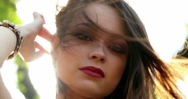 Dışarıda güzel bir kız yüzü parlayan mercekle parlıyor. Dışarıda poz veren genç bir kadının portresi.