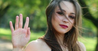 Güzel kız el sallıyor Açık hava parkında kameraya