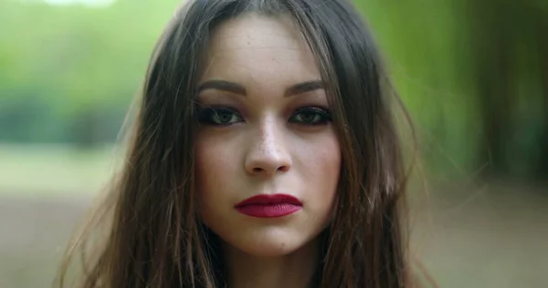 Portrait of serious young woman in 20s looking to camera in outdoors