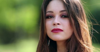 Parkta poz veren sevimli İspanyol kız kameraya bakıyor. Kendine güvenen Latin bir genç kadın.