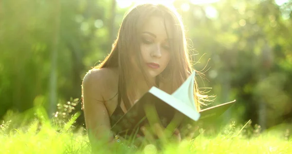 かなり若いです女性読書本で屋外公園草 — ストック写真