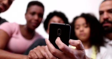 Sıradan ebeveynler ve kardeşler telefondan içeriği izliyorlar.
