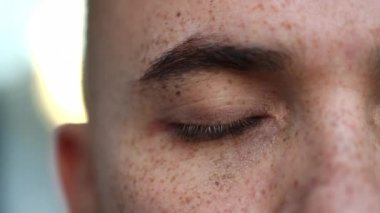 Man opening eyes macro close-up. Pensive person meditating closing eye in contemplation