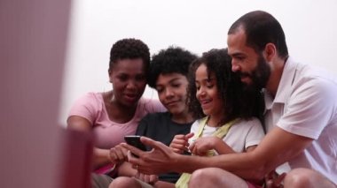 Candid parents and children using smartphone, real people staring at phone