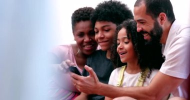 Family looking at cellphone together. Parents and children gathered around smartphone