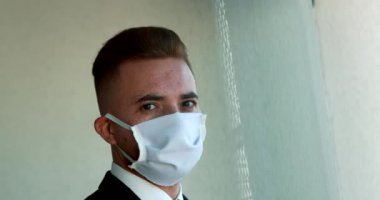 Portrait of man wearing covid-19 mask turning head towards camera, person looks to camera