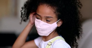 Little girl wearing covid-19 face mask. Portrait kid putting mask on