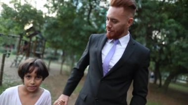 Father and son holding hands at park, ethnically diverse parent and child together, real life and authentic