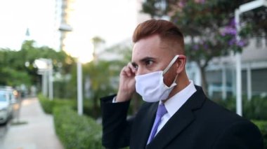 Man putting covid-19 mask prevention outdoors. Portrait of person wearing suit outside wearing pandemic mask