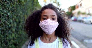 Covid-19 maskeli melez kız kameraya bakıyor.