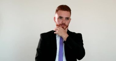 İrlandalı yönetici sakala dokunuyor, kızıl saçlı adam yüzüne dokunuyor.