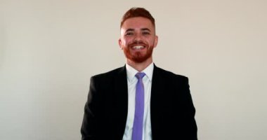 Kızıl saçlı adam iş elbisesi giyiyor, ruh hali değişiyor, mutluluktan ciddiyete geçiyor.