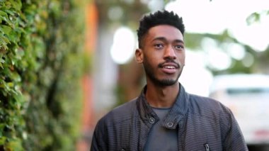Happy confident young African man walking outside in urban street