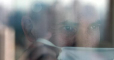 Ameliyat maskesini takan adam pencerenin camını gördü.
