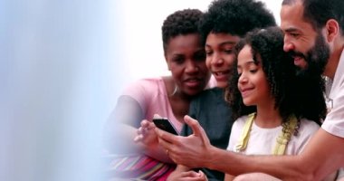 Mixed race family and children laughing together over cellphone content