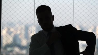 Silhouette of business man putting on business suit. Young man morning routine putting on clothes