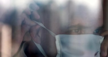 Camdan yansıyan camla görülen kişi CV19 cerrahi maskeli.