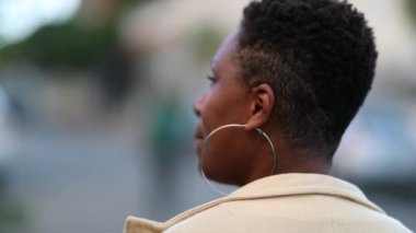 Back of thoughtful African woman walking outside. Black lady daydreaming