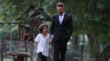 Real life father and son walking together outside at park