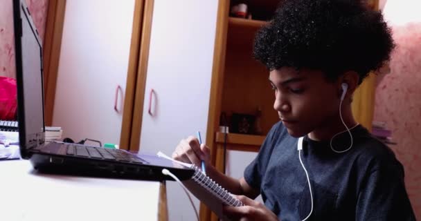 Boy Doing Homework Home Browsing Laptop Writing Notes Looks Camera — Stockvideo