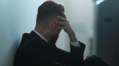 Regretful man feeling despair and isolation sitting on home floor feeling desolate