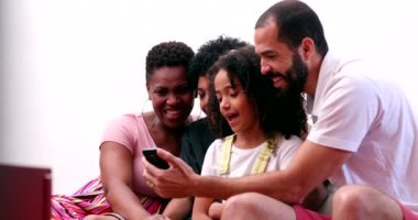 Family looking at cellphone together. Parents and children gathered around smartphone