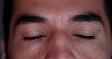 Man closing eyes in meditation. Contemplative person opening eyes smiling, macro face close-up