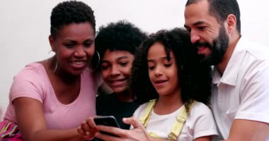Interracial family using cellphone. Mixed race parents and children looking at smartphone device