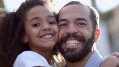 Father and daughter smiling at camera, mixed race ethnically diverse parent and child