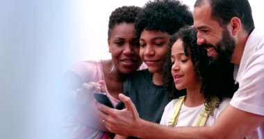 Family looking at cellphone together. Parents and children gathered around smartphone