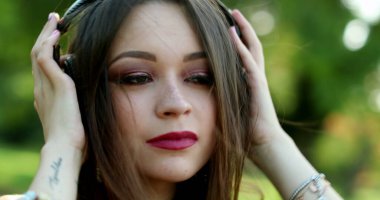 Kulaklık takan kadın parkta oğlunu dinliyor.