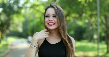 Genç milenyum kadını otantik gerçek hayat parkında gülüyor ve gülüyor. Gülümseyen ve gülen güzel bir kız.