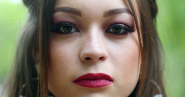 Genç bir kadın kameraya bakarak gözlerini kapatır. Güzel milenyum kızı portresi.