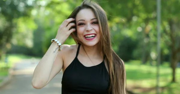 Young millennial woman authentic real life laugh and smile in outdoor park. Pretty girl smiling and laughing natural expression