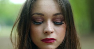 Genç kadın kameraya bakarak gözlerini açıyor. 20 'li yaşlarda oldukça ciddi bir kız.