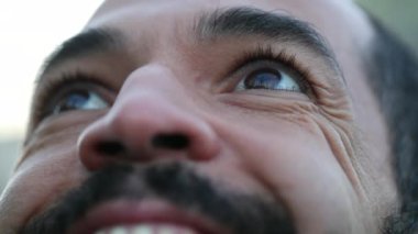 Man eyes looking at sky smiling, contemplative person close-up face and eye with HOPE