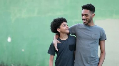 Older brother walking with younger sibling together giving advice about life. Mixed race ethnicity