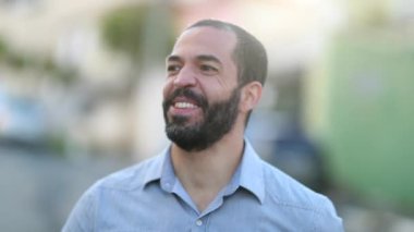 Man smiling and laughing outdoors with lens-flare. Person in 40s smile and laugh